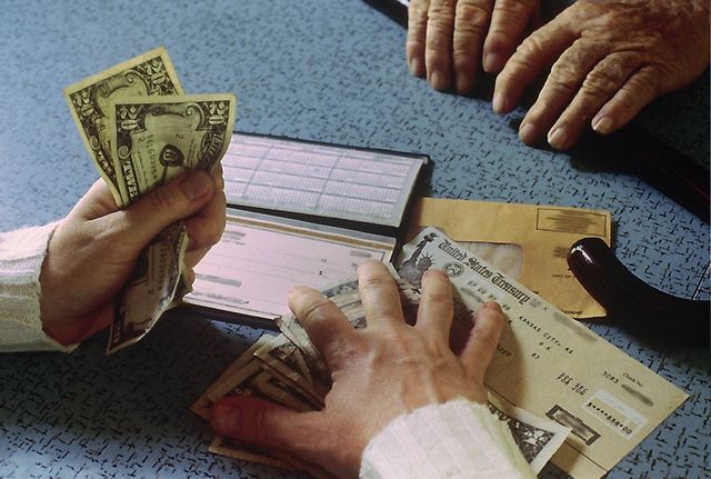 A hand stealing money from another hand, symbolizing financial exploitation
